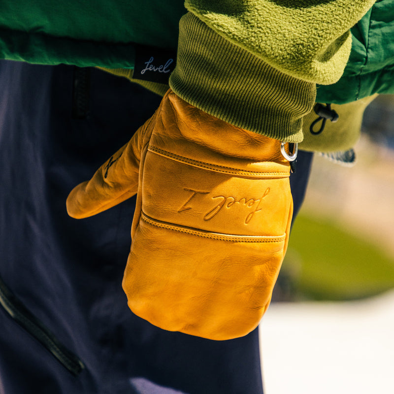 Yellow glove with 'Level 1' embroidery worn by a person in green jacket.